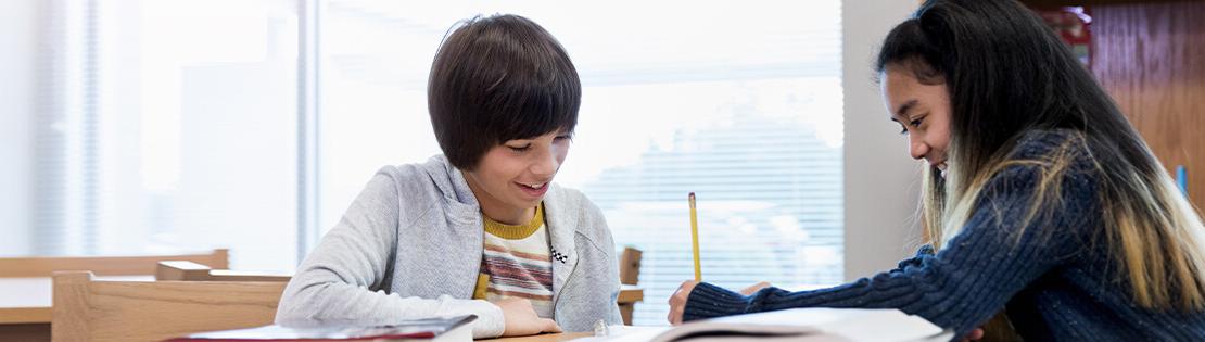 两个未满十岁的孩子在教室里兴奋地一起进行写作活动